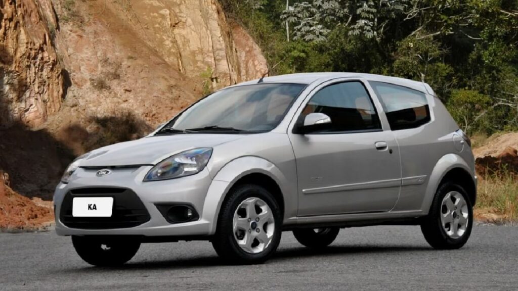 Ford Ka cinza estacionado em uma rua com montanha ao fundo