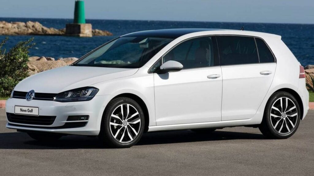 Foto lateral de um Golf 2014 perto do mar, sua cor é branca