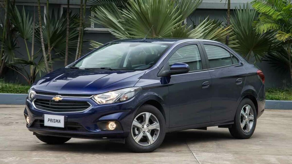 Foto de um Prisma 2018 estacionado em um pavimento, provavelmente em uma residência