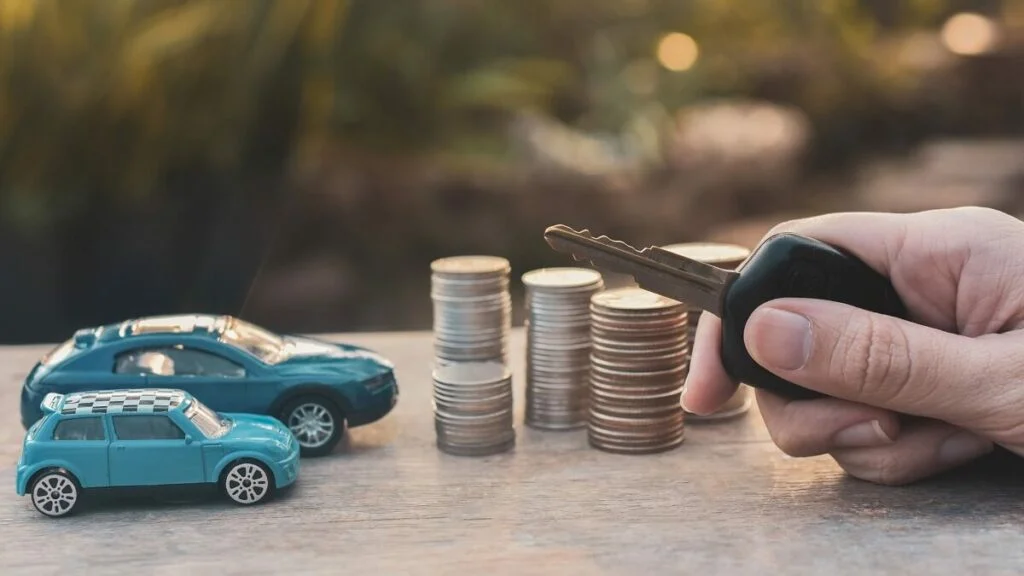 Tabela Fipe: carro de brinquedo com moedas ao lado e m&atilde;o de homem segurando uma chave