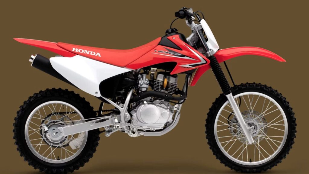 Honda CRF 150F 2014 vermelha em fundo marrom.