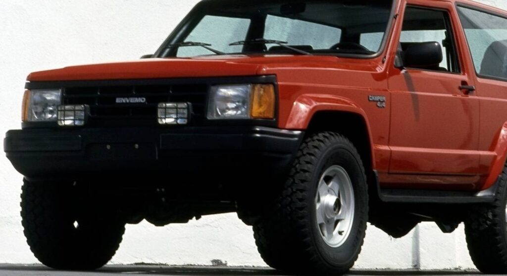 Envemo Camper 1990 vermelho parado na diagonal.