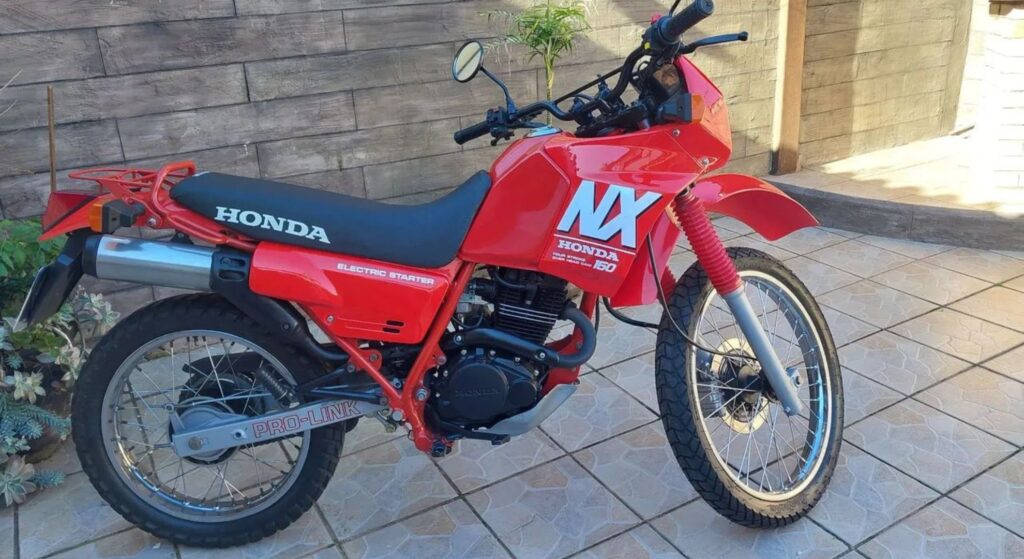 Honda NX 150 1990 vermelho parado de costas.