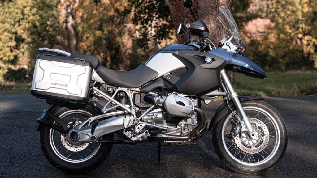 BMW R 1200 GS 2005 azul parada de lado na estrada.