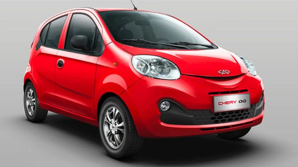 Caoa Chery QQ 2019 vermelho na diagonal em um fundo cinza.
