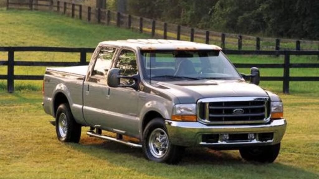 Ford F250 2002 cinza na diagonal em um gramado.