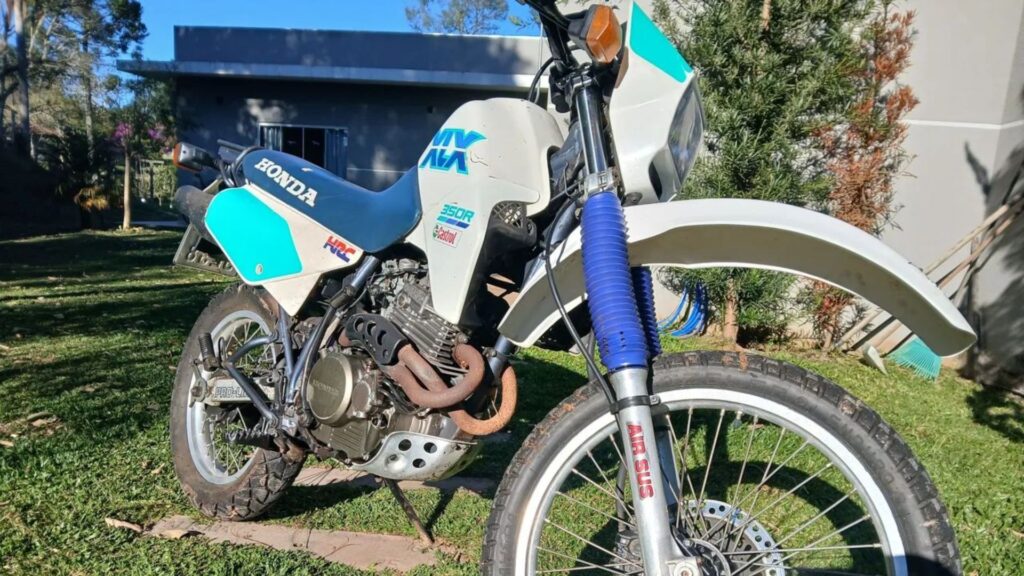 HONDA XLX 350 R 1991 branca com azul na diagonal parada em um quintal.