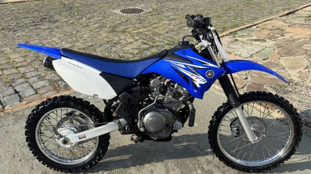 Yamaha TT-R 230 2009 azul de lado na beirada da estrada.