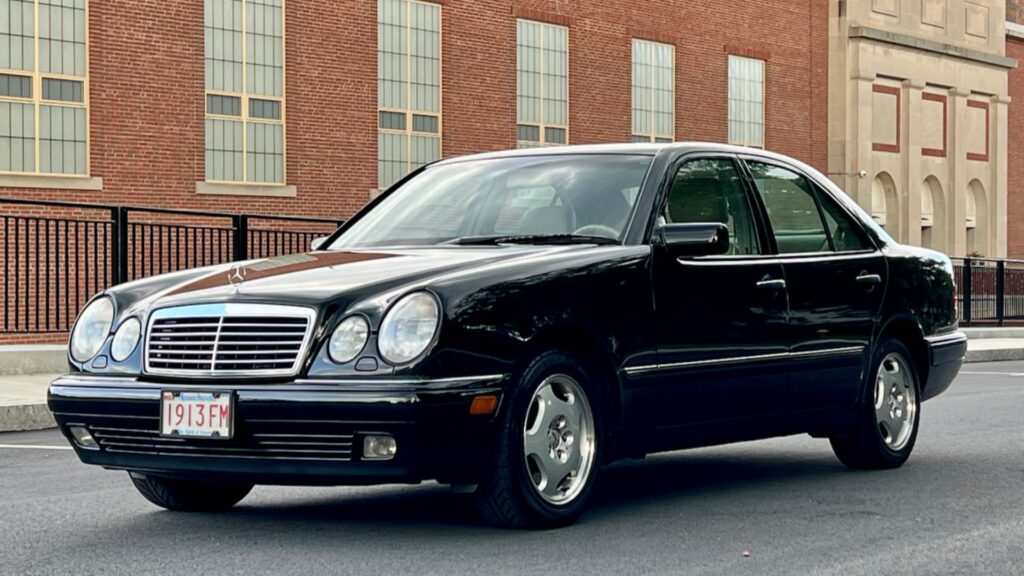 Mercedes-Benz E-430 1998 preto na diagonal em uma estrada.
