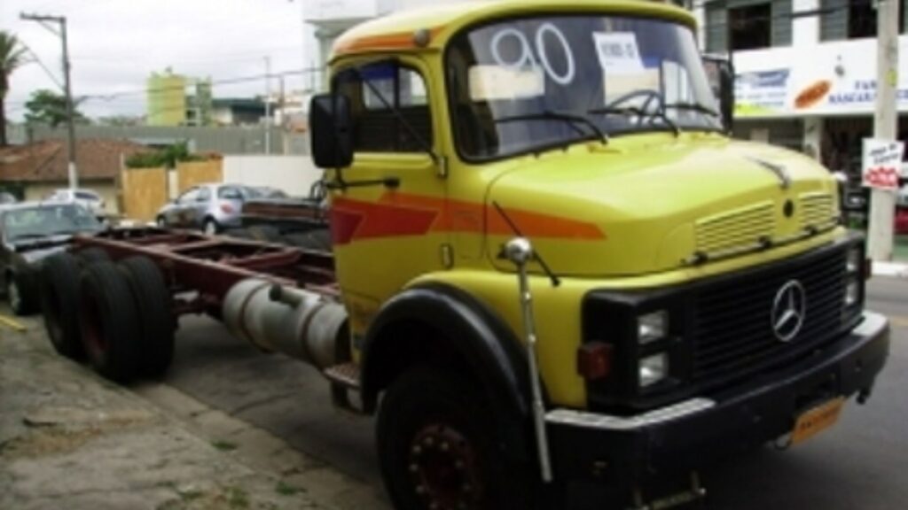 MERCEDES-BENZ L-2017 1990 amarelo com detalhes em laranja estacionado na beirada da estrada.