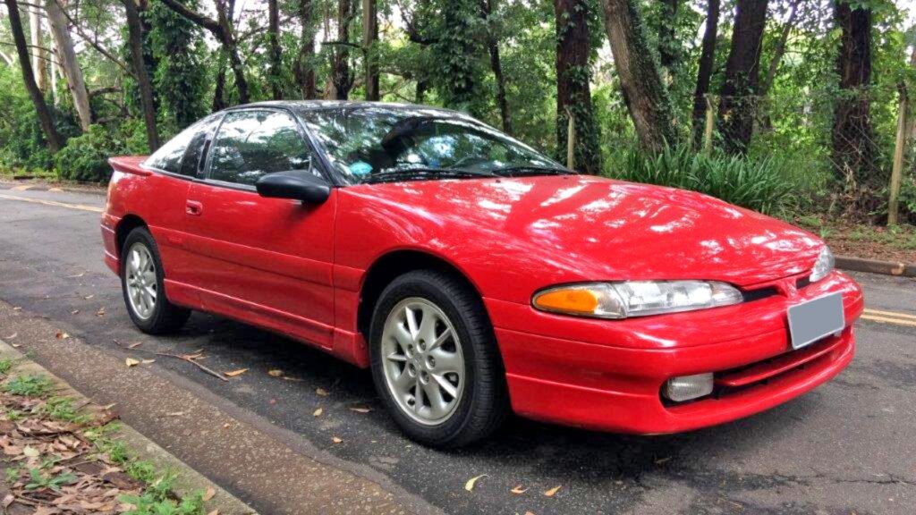 Mitsubishi Eclipse 1992 vermelho parado na beirada de uma estrada.