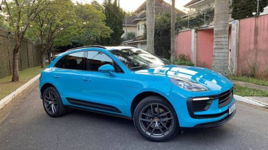 Porsche Macan 2022 azul parada na diagonal no meio da rua.
