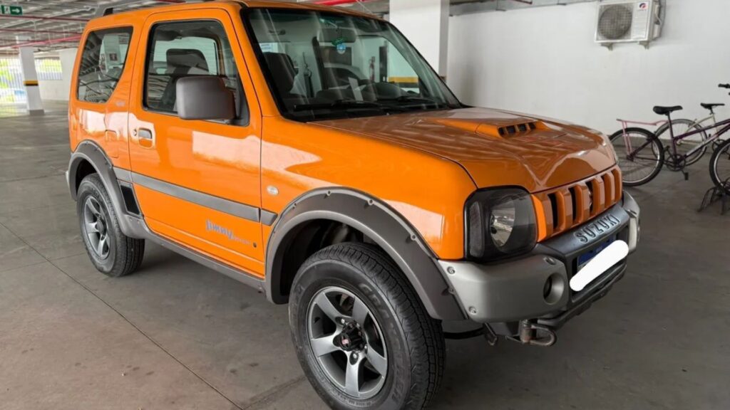 Suzuki Jimny 2016 laranja parado em uma garagem de carros.