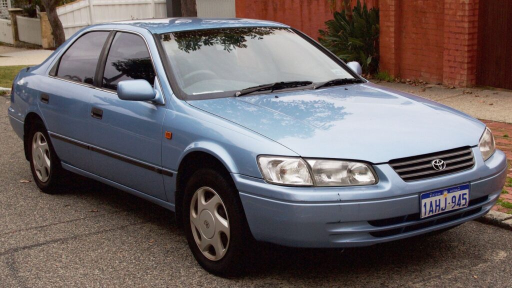Toyota Camry 2000 azul claro parado na beirada da estrada.