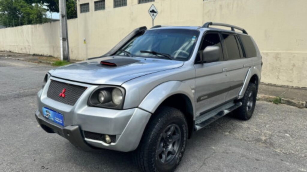 Mitsubishi Pajero 2007 prata parada na diagonal no meio da rua.