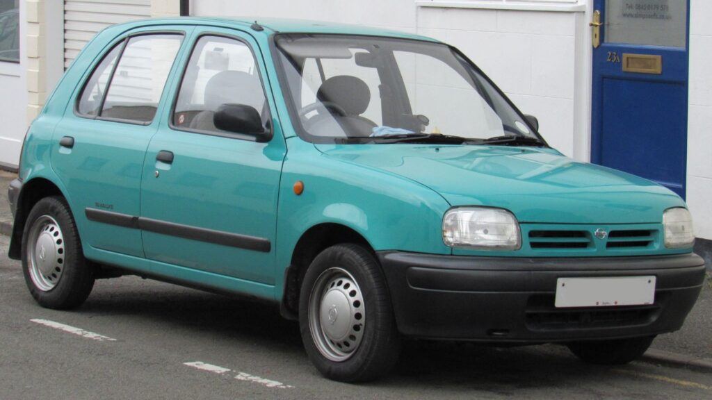 Nissan Micra 1995 verde água parado na beirada da estrada.
