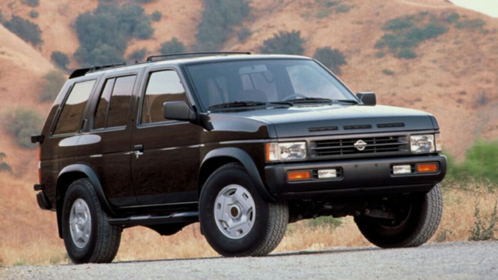 Nissan Pathfinder 1995 preta parada na diagonal em um asfalto.