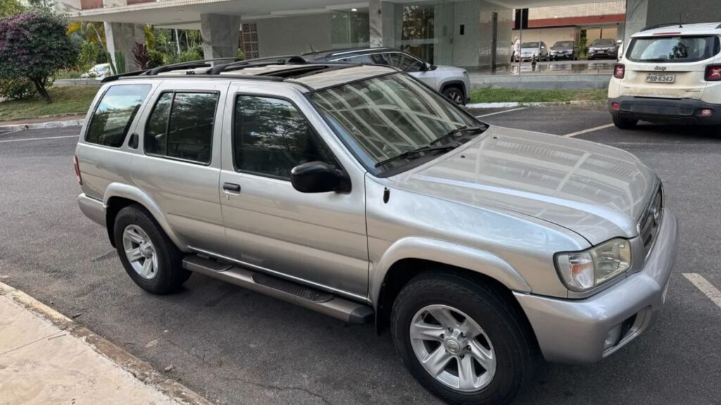 Nissan Pathfinder 2004 prata parada na beirada da estrada.