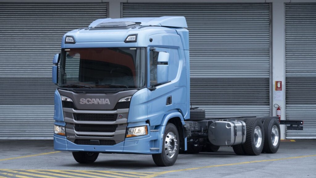 SCANIA P-280 2020 azul clara parada na diagonal na frente de uma garagem?