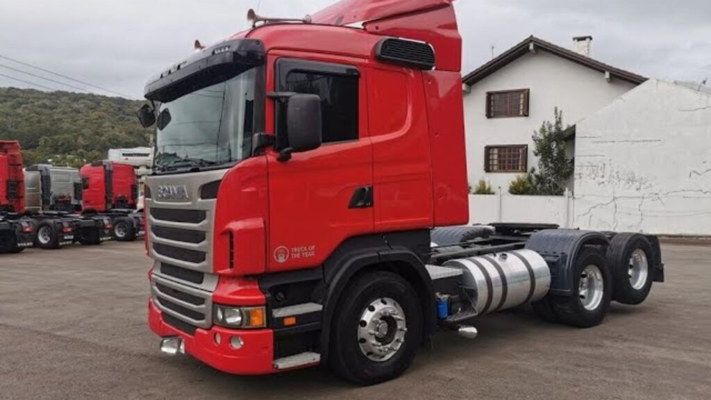 SCANIA R-380 2011 vermelha para na diagonal em meio de um pátio.