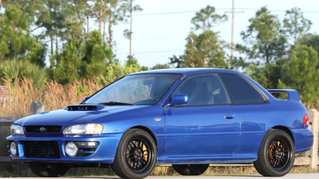 Subaru Impreza 1995 azul parado na diagonal na beirada da estrada.