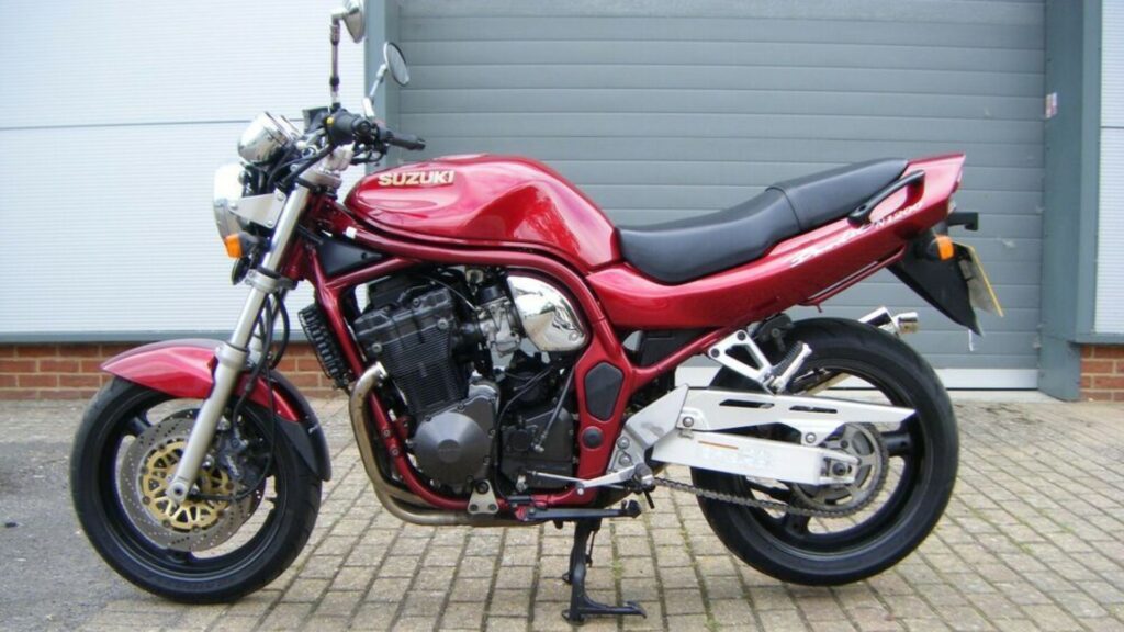 SUZUKI BANDIT 1997 vermelha parada de lado com um galpão no fundo.