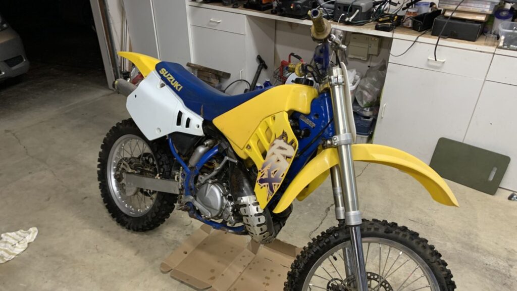SUZUKI RMX 250 1990 amarela parada na diagonal.