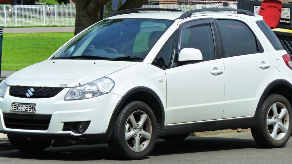 Suzuki SX4 2009 branco parado estacionado na beirada da estrada.