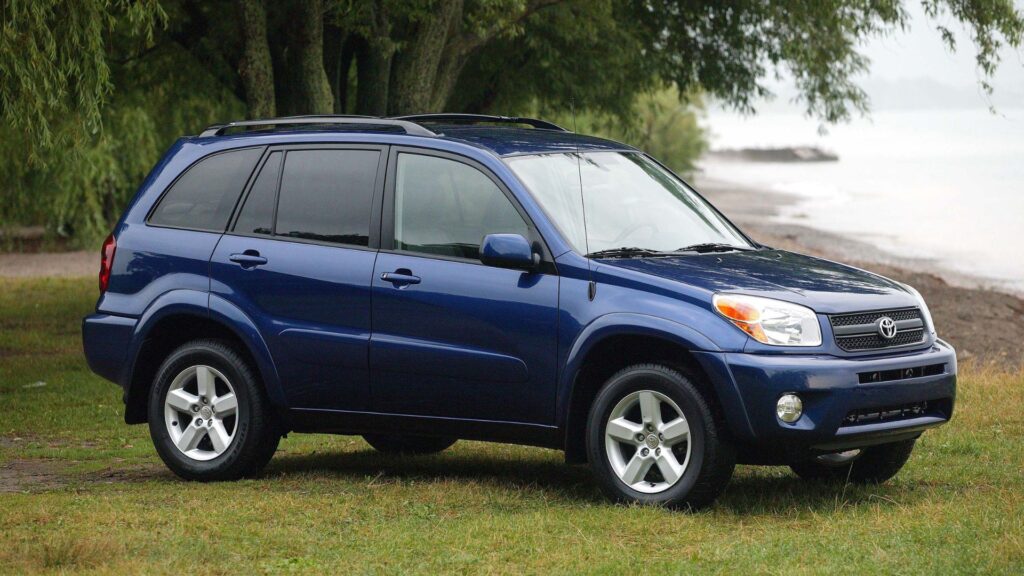 Toyota RAV4 2005 azul parado na diagonal em cima de uma gramado.