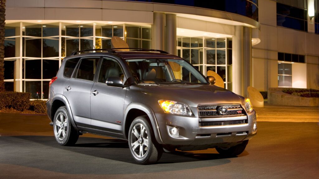 Toyota RAV4 2010 cinza parado na diagonal á noite.