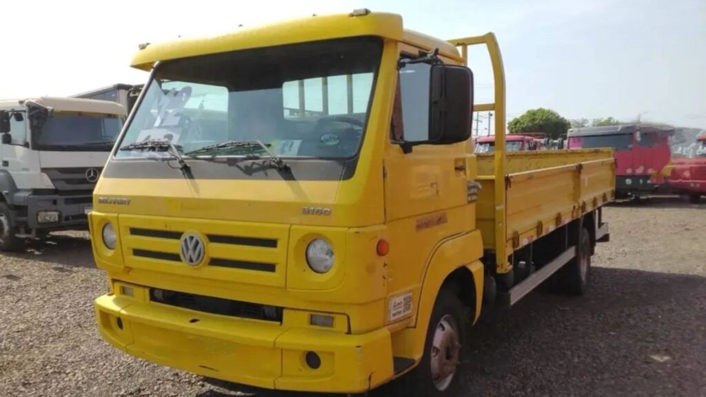 VOLKSWAGEN 9-160 2012 amarelo parado em um pátio cheio de caminhões.
