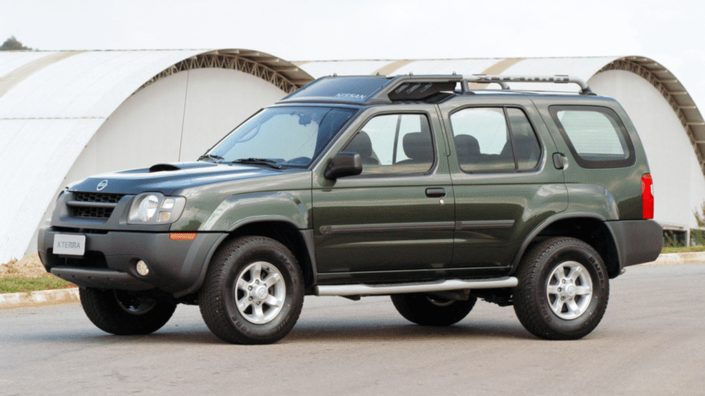 Nissan XTerra 2007 parado na diagonal com dois galpões no fundo.