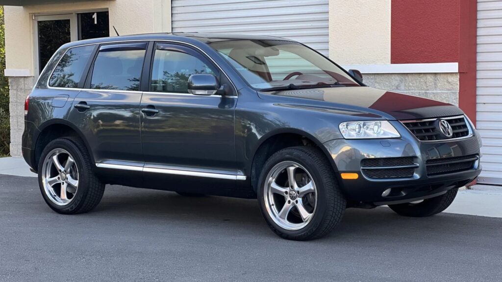 VolksWagen TOUAREG 2007 cinza parado do lado de um estabelecimento.