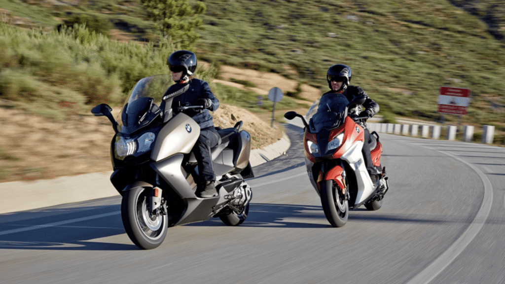 Duas BMW C 650 2014 em movimento na estrada.