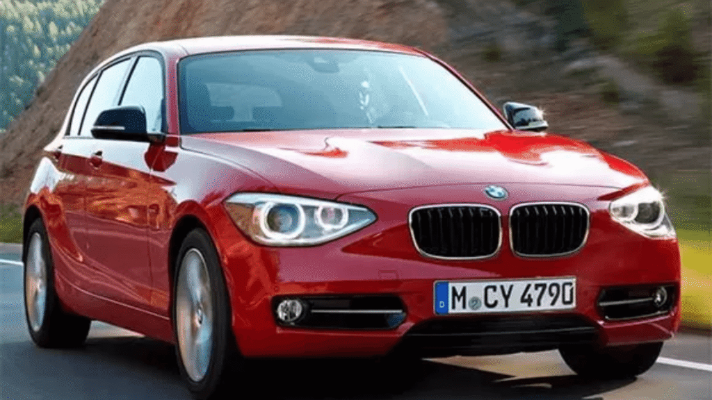 BMW 120i 2005 vermelho em movimento na estrada.
