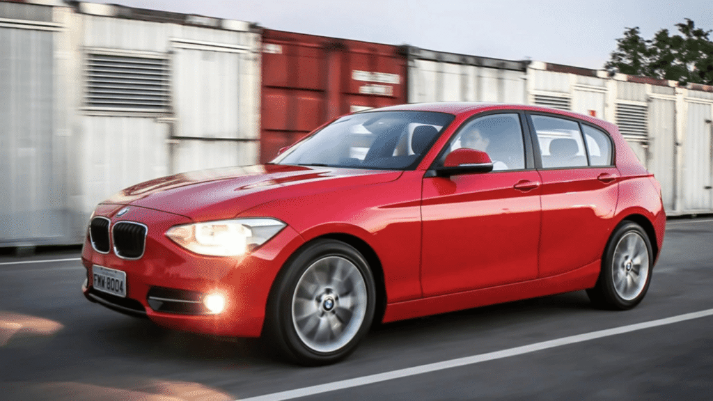 BMW 118iA 2013 vermelho em movimento na estrada.