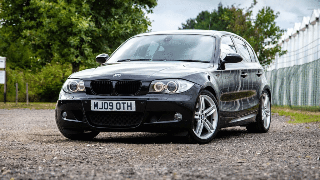 BMW 130iA 2012 preto parado na diagonal.