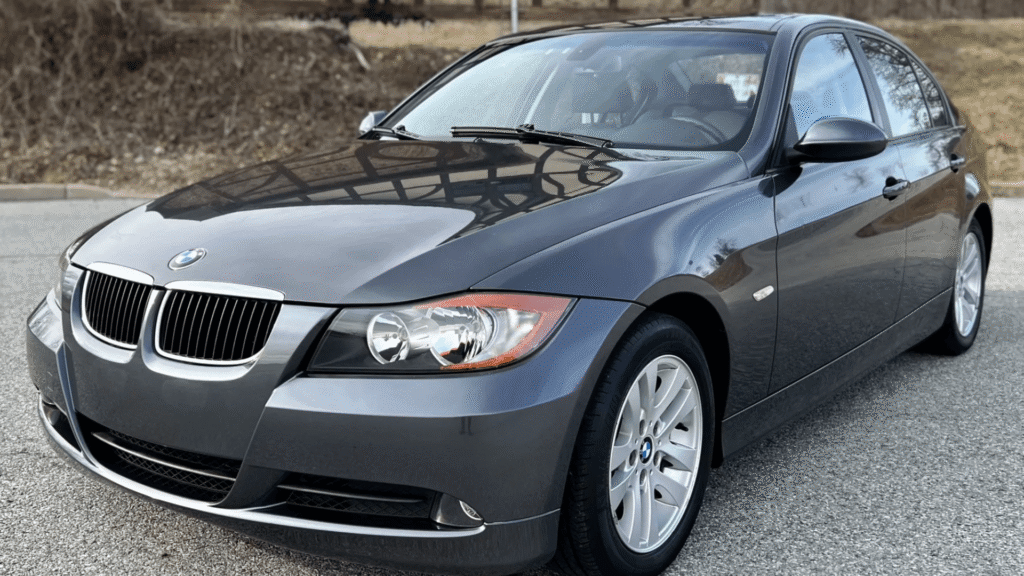 BMW 325iA 2006 cinza parada na diagonal no meio da estrada.