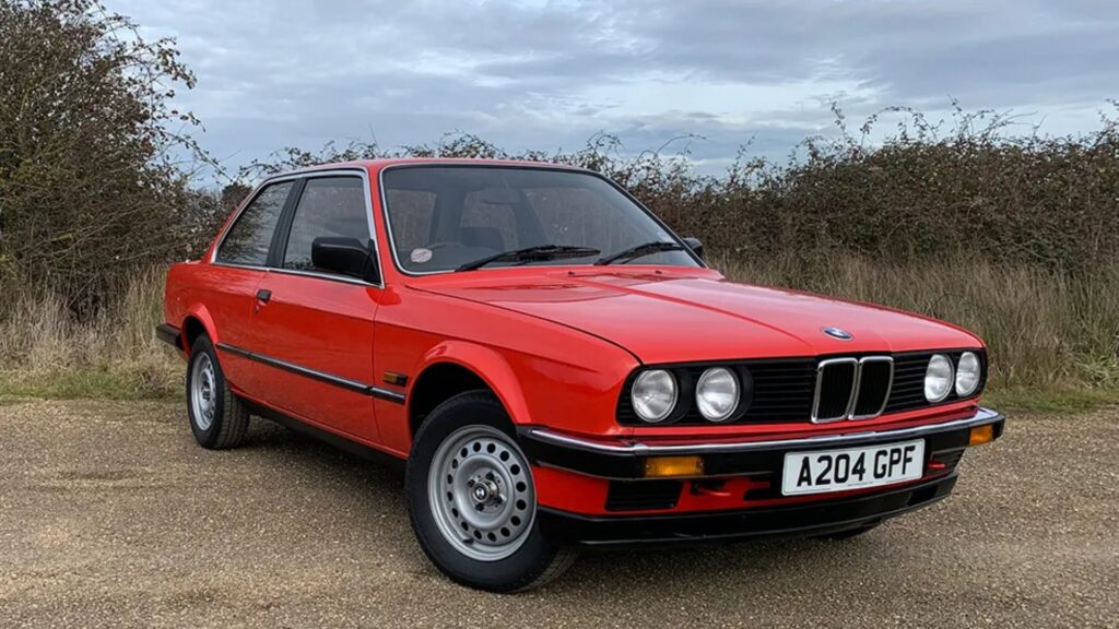 BMW 316 1986 vermelho parado na diagonal.