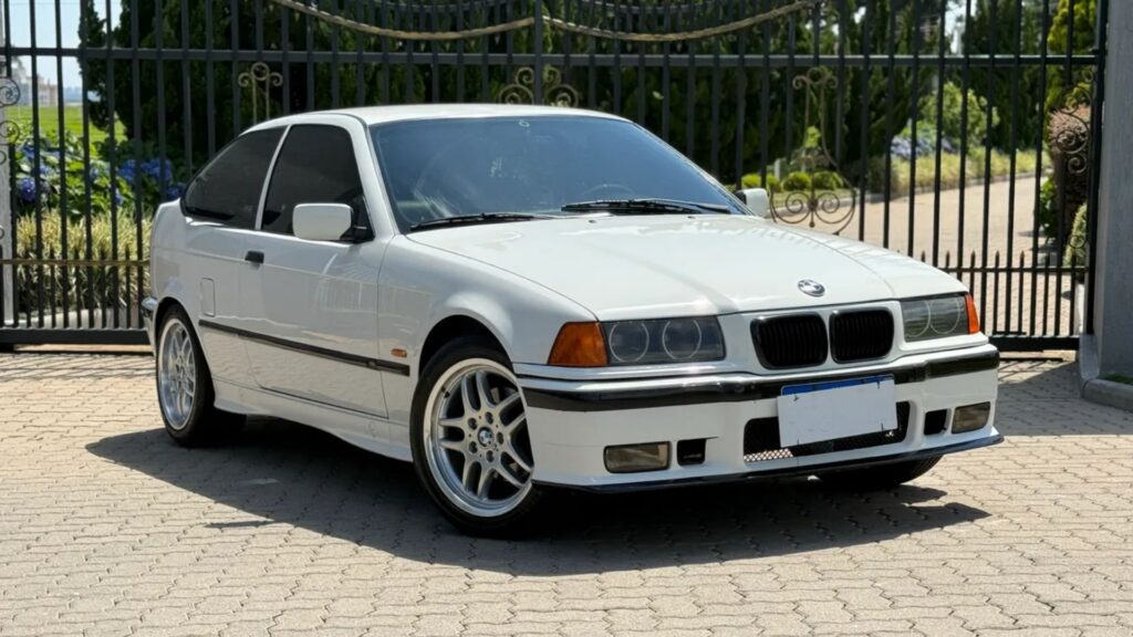 BMW 318i/iA 1998 branco parado na diagonal.