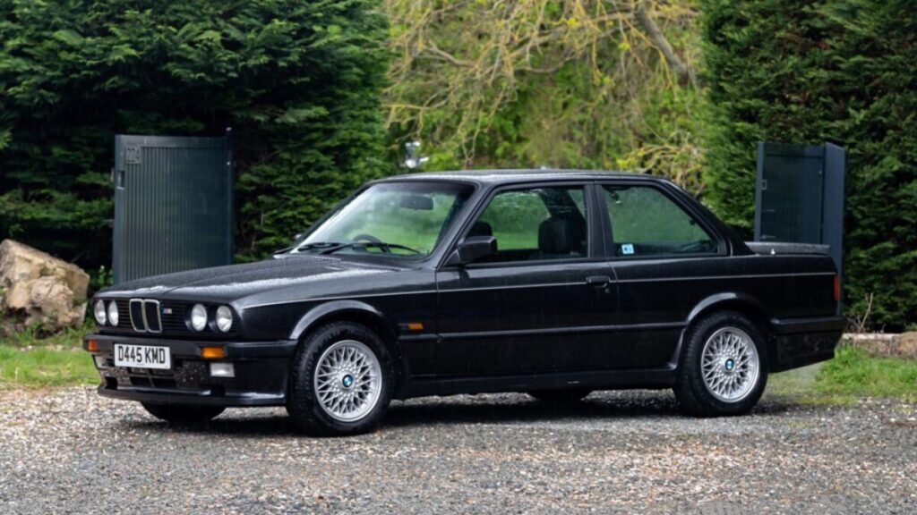 BMW 325i 1987 preto parado na diagonal.