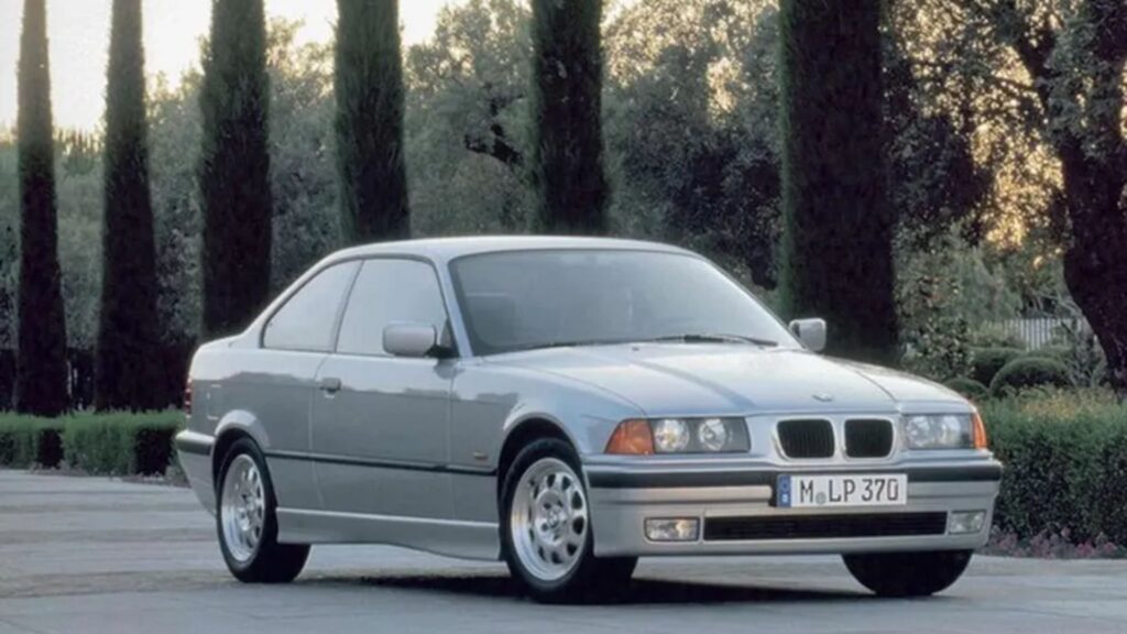 BMW 325i 1996 prata em movimento na estrada.